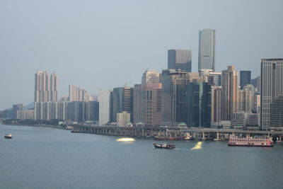 Sea and buildings in city against clear sky