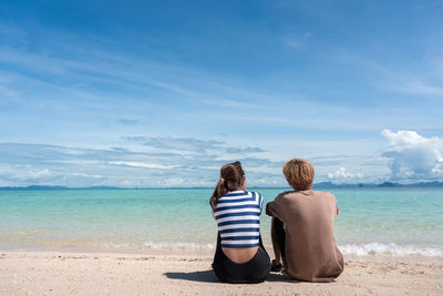 Rear view of women sitting on beach