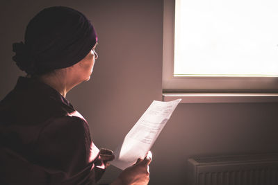 Side view of woman reading medical letter at window