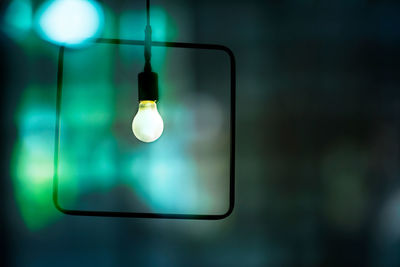 Close-up of light bulb hanging against glass