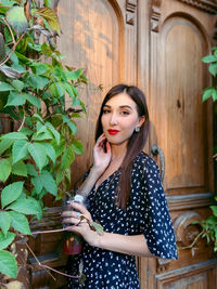 Portrait of beautiful young woman near door