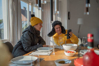 A couple is sitting at the dining table in winter clothes at home, it is cold, they are freezing