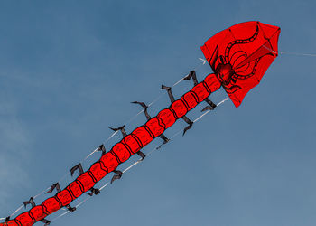 A red unique insect-like kite flies ominously overhead