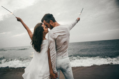 Friends standing on beach against sky