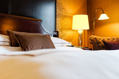 Pillows on bed in illuminated bedroom at home