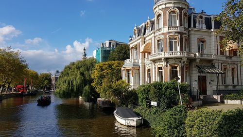 Canal amidst trees and buildings against sky