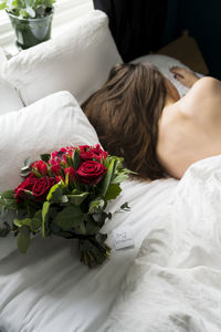 Bouquet of red roses on bed, sleeping woman on background