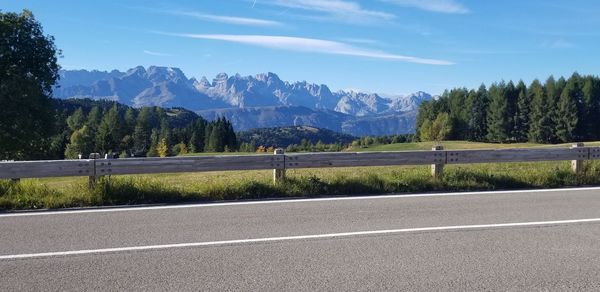 Road by trees and mountains against sky