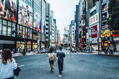 Rear view of people walking on road in city