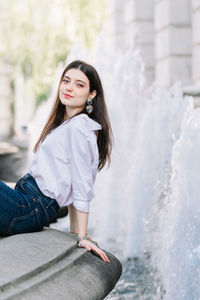 Portrait of beautiful woman sitting by fountain