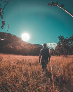 Rear view of man standing on field against sky