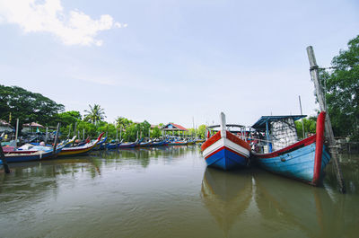Boats moored in river against sky