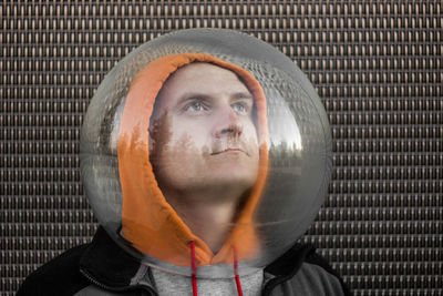 Man wearing spherical shape glass against wall