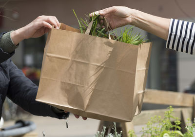 Close-up of hands holding paper bag outdoors