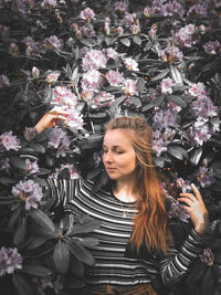 Portrait of beautiful woman standing by flowering plants