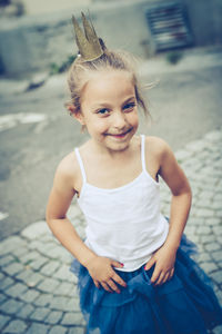 Portrait of cute girl wearing crown on sidewalk