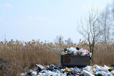 Stack of garbage on field against sky