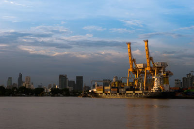 Illuminated buildings by sea against sky in city