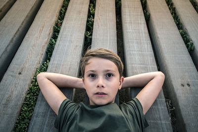 High angle portrait of boy lying on wooden floor