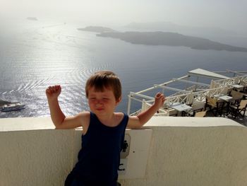 Boy standing by sea against mountain