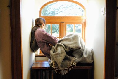 Woman sitting on window seat at home