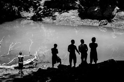 Rear view of people standing by pond