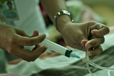 Midsection of nurse injecting syringe at hospital