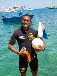 Portrait of smiling young man holding boat in sea