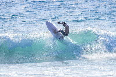 Shirtless boy surfing in sea