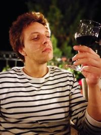 Close-up of young man holding wineglass at night