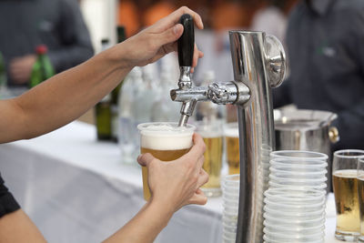 Cropped hands of woman filling glass with beer