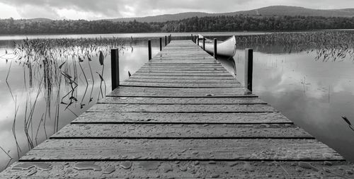 Wooden jetty on pier over lake against sky