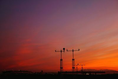 Silhouette street lights against orange sky