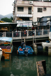 Boats moored in river by buildings in city