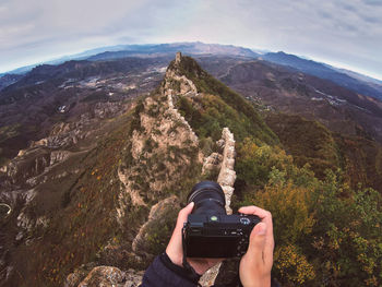 Man photographing on mountain against sky