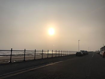 Road by sea against sky during sunset