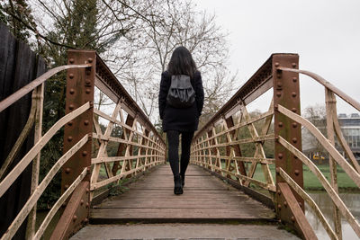 Rear view of woman walking on footbridge