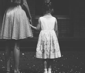 Midsection of mother with daughter standing on sidewalk