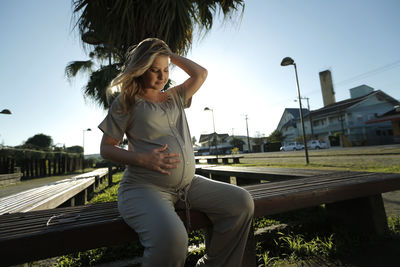 Pregnant woman sitting on bench at park