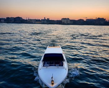 Boat sailing in river against sky during sunset