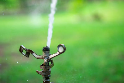 Water sprinkler spraying water on grass field in park