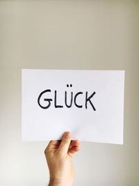 Close-up of hand holding paper against white background