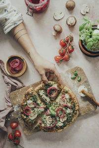 Hands reaching for homemade pizza