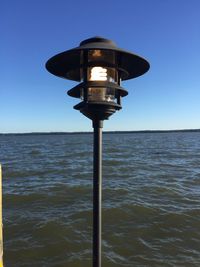 Illuminated lamp post against clear sky