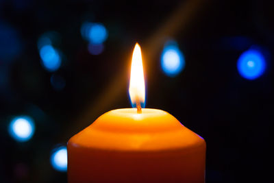 Close-up of lit candle in darkroom