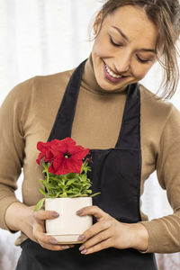 Close-up of smiling young woman holding red rose