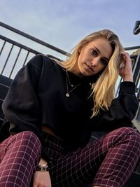 Portrait of beautiful woman sitting on railing