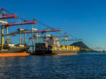 Cranes at commercial dock against clear blue sky