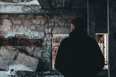 Rear view of man looking at abandoned building