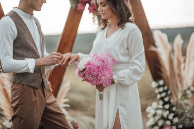 Midsection of couple holding bouquet of people